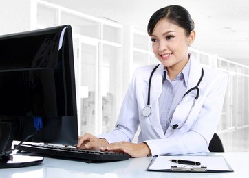 front view of smiling woman doctor working on computer