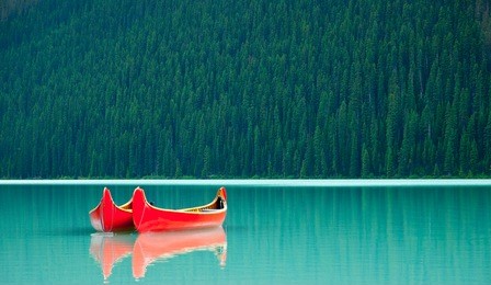 canoes floating peacefully on the waters of lake louise, banff national park, alberta, canada.
