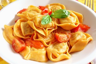 a dish of freshly cooked italian ravioli with cherry tomato sauce and basil