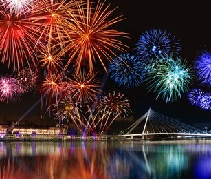 colorful fireworks reflect from water,  beautiful bridge scenery