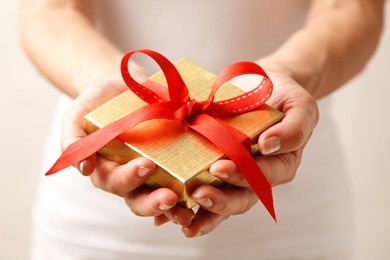 woman holding a gift box in a gesture of giving.