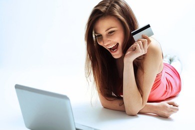 a happy woman holding a credit card and shopping from the internet