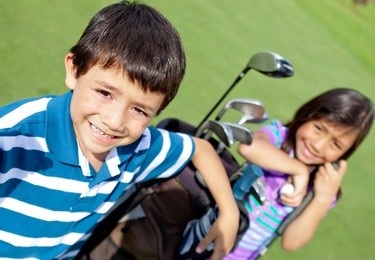 kids playing golf and holding a bag at the course