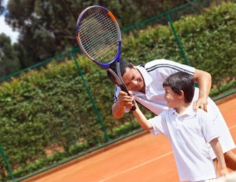father teaching his son how to playing tennis