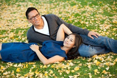 ethnic young couple sitting in a pile of leaves