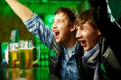happy men shouting while watching football match broadcast in pub