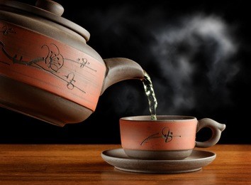 pouring a cup of tea from ceramic teapot in asian style