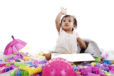 adorable baby girl playing with book and blocks isolated on white