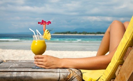 woman holding a fruit cocktail on a tropical beach