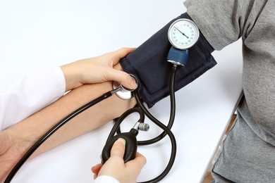 doctor checking blood pressure with stethoscope and sphygmomanometer