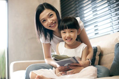 attractive asian mother reading with her daughter