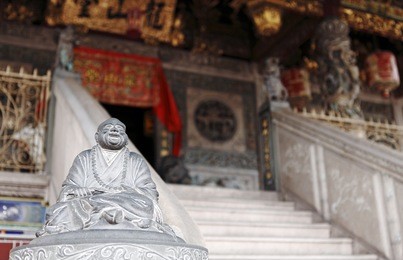 an ancient buddha statue at the steps to an exotic old chinese temple in georgetown city, penang, malaysia.