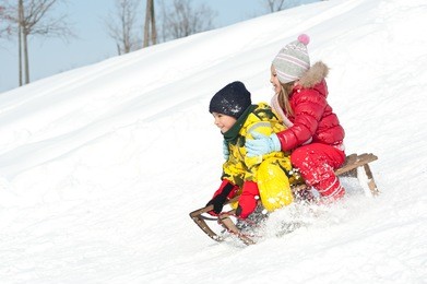 two kids sliding with sledding in the snow.