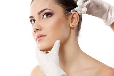 beautiful young female face and hands in gloves with beauty treatment injection isolated on white