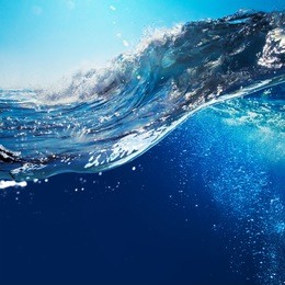 ocean-view seascape landscape with blue sky and sunlight big curly ocean wave splitted by waterline to underwater part with air bubbles