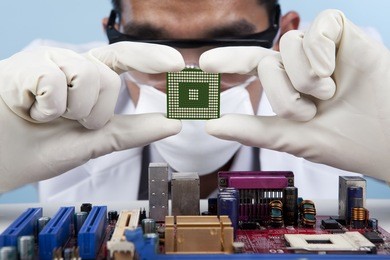 a scientist checking the computer chip of a motherboard