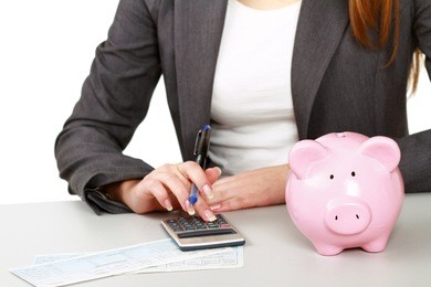 young woman with a piggy bank and using a calculator