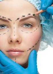 beautiful young woman with perforation lines on her face before plastic surgery operation. beautician touching woman face.