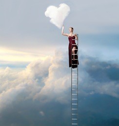 beautiful elegant woman on a ladder in the sky drawing a heart-shaped cloud