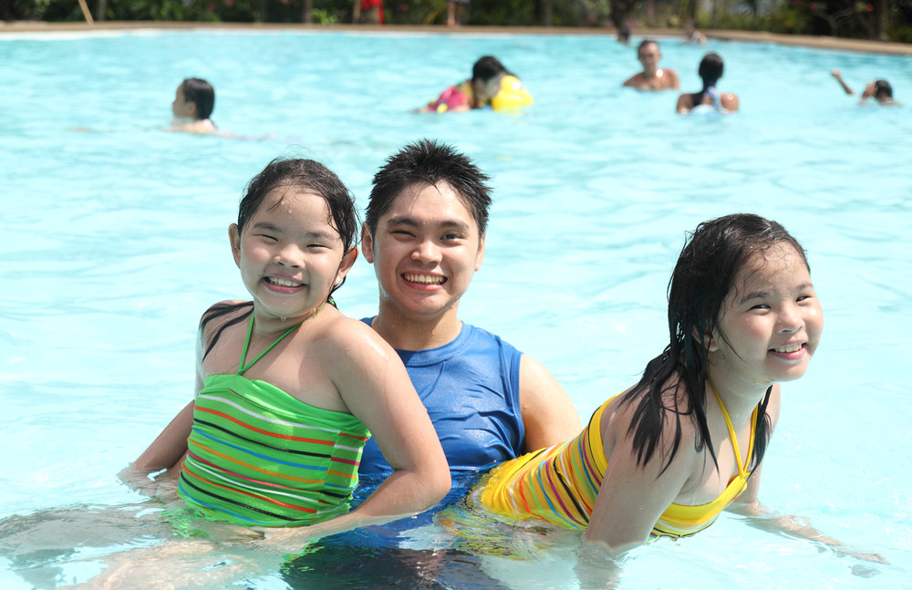 twin kids with uncle enjoying in the swimming pool