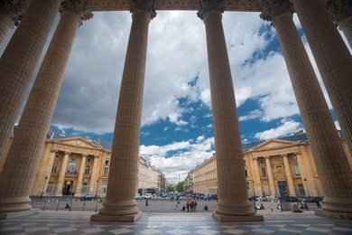 the grand columns of the pantheon and neighboring parisian buildings are uniquely seen from the inside looking out point of view in paris, france. horizontal