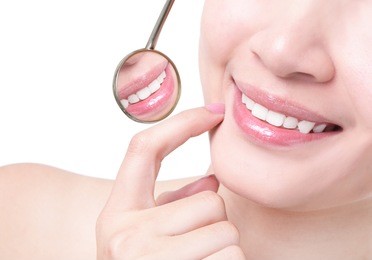 healthy woman teeth and a dentist mouth mirror isolated on white background, model is a asian girl