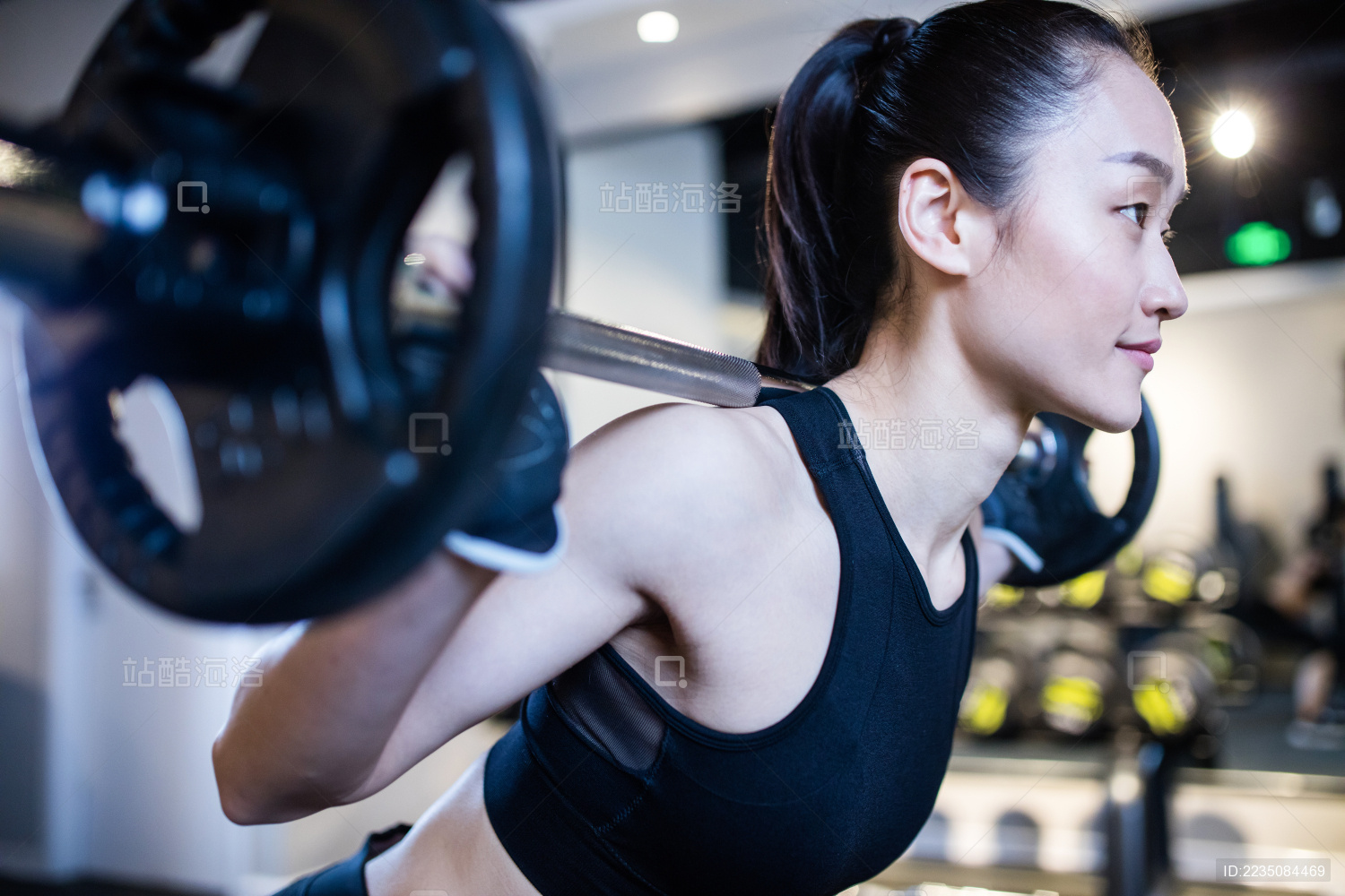 一名年轻女性在健身房举杠铃