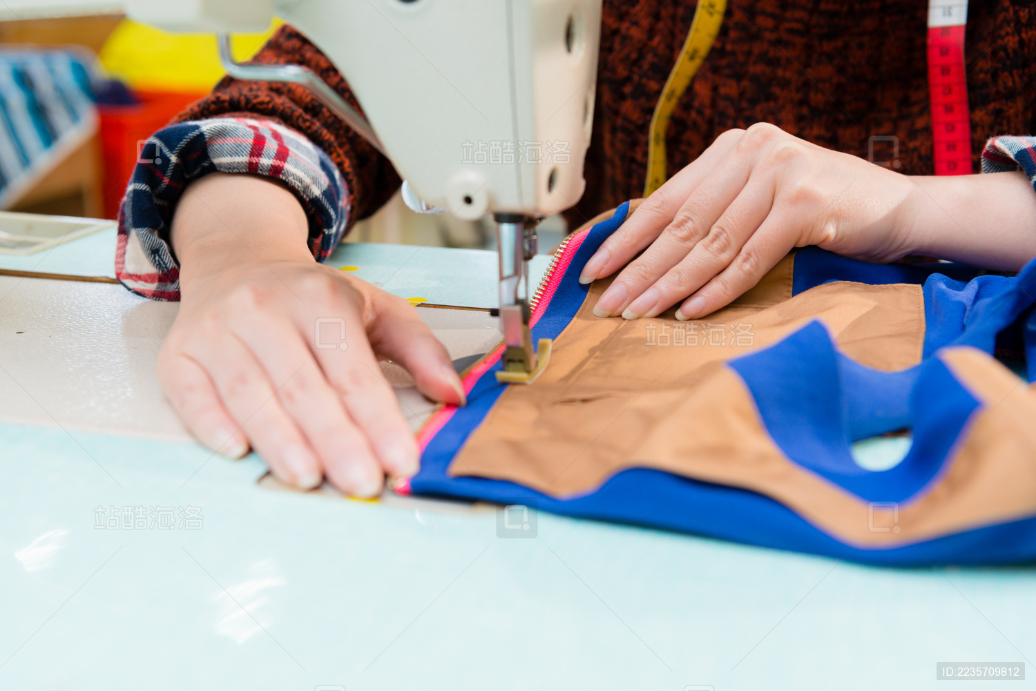 服装厂员工的女子使用特制机器制造公司为新一季产品有选择性的重点照片拿着礼服来样特写镜头。