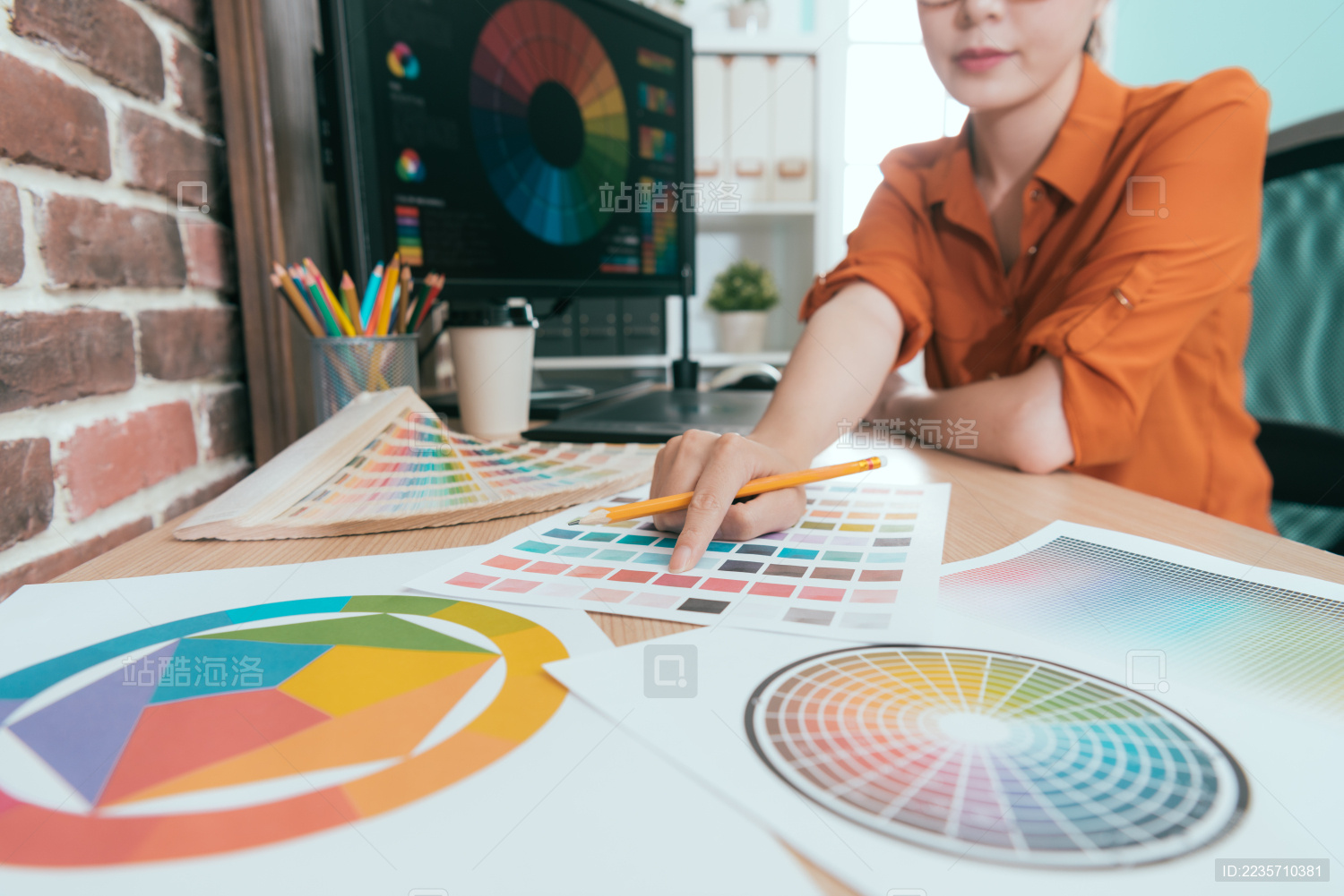 面带微笑的漂亮女人工作设计室举行铅笔 指着与选择性的重点彩色照相纸调色板的特写镜头。