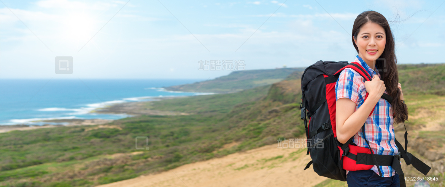 女登山妇女背着背包徒步旅行在山的最高点 站在回沿海景观在阳光明媚的早晨节日横幅作物复制空间。