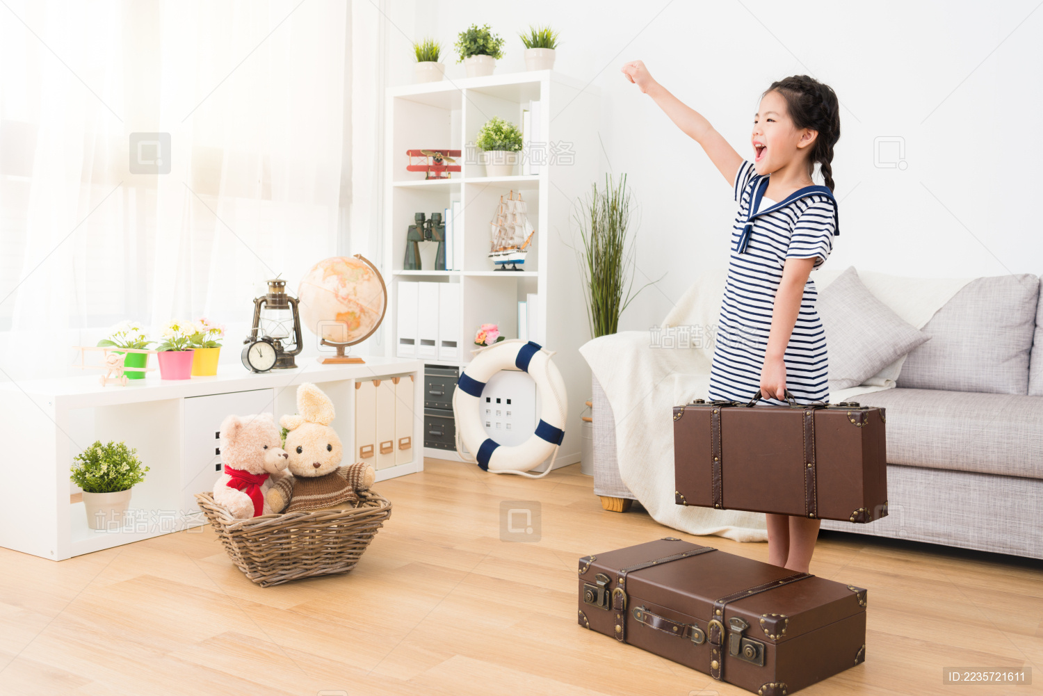 开朗可爱的小女孩穿着旅客水手服装 手持行李箱的行李站在木地板准备前往。