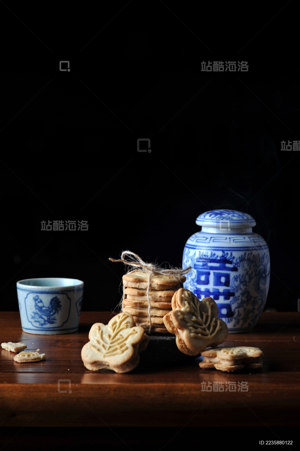 桌子上的一个青花喜字瓷罐前的一摞枫叶形饼干和一个青花茶杯