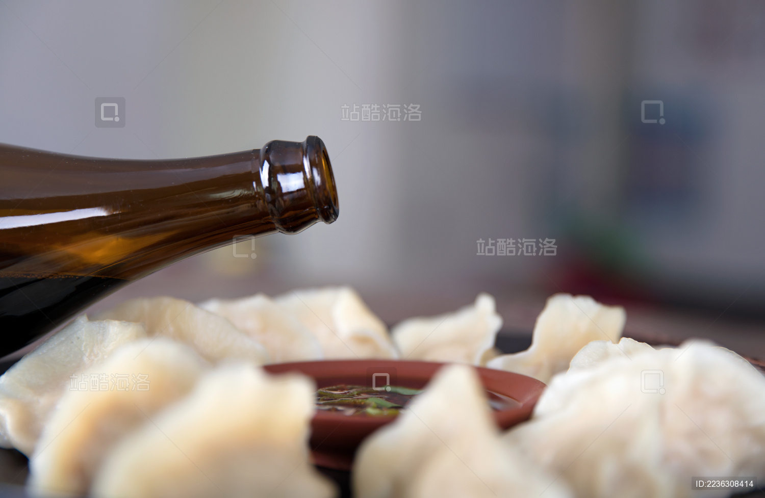 一盘中国传统美食饺子和正往蘸料中加醋的瓶子