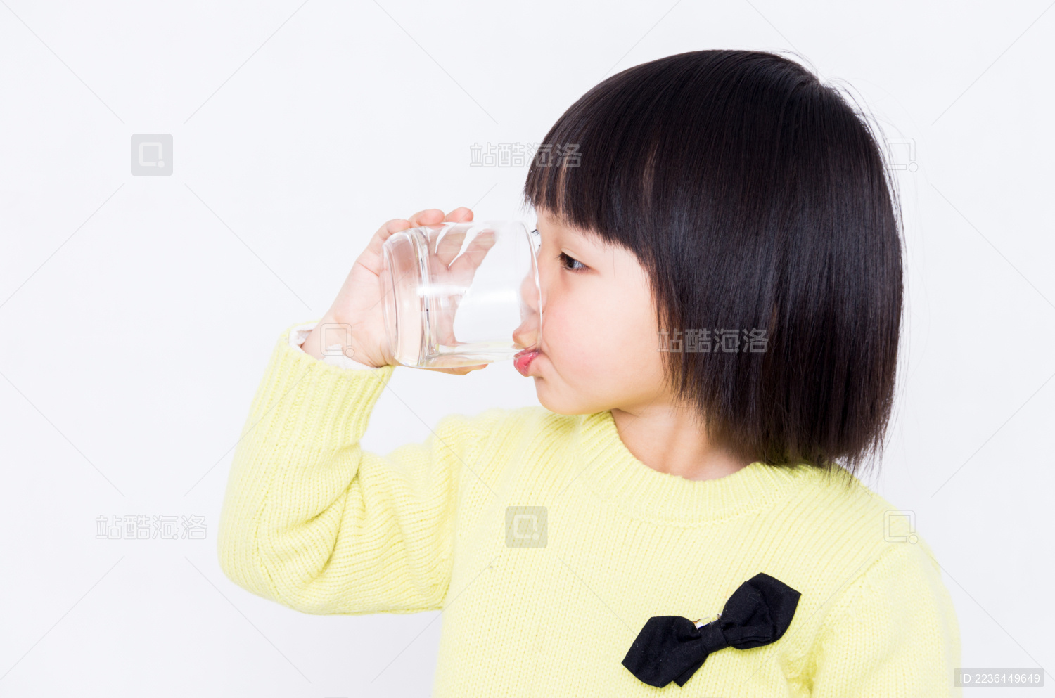 拿玻璃水杯喝水的小女孩
