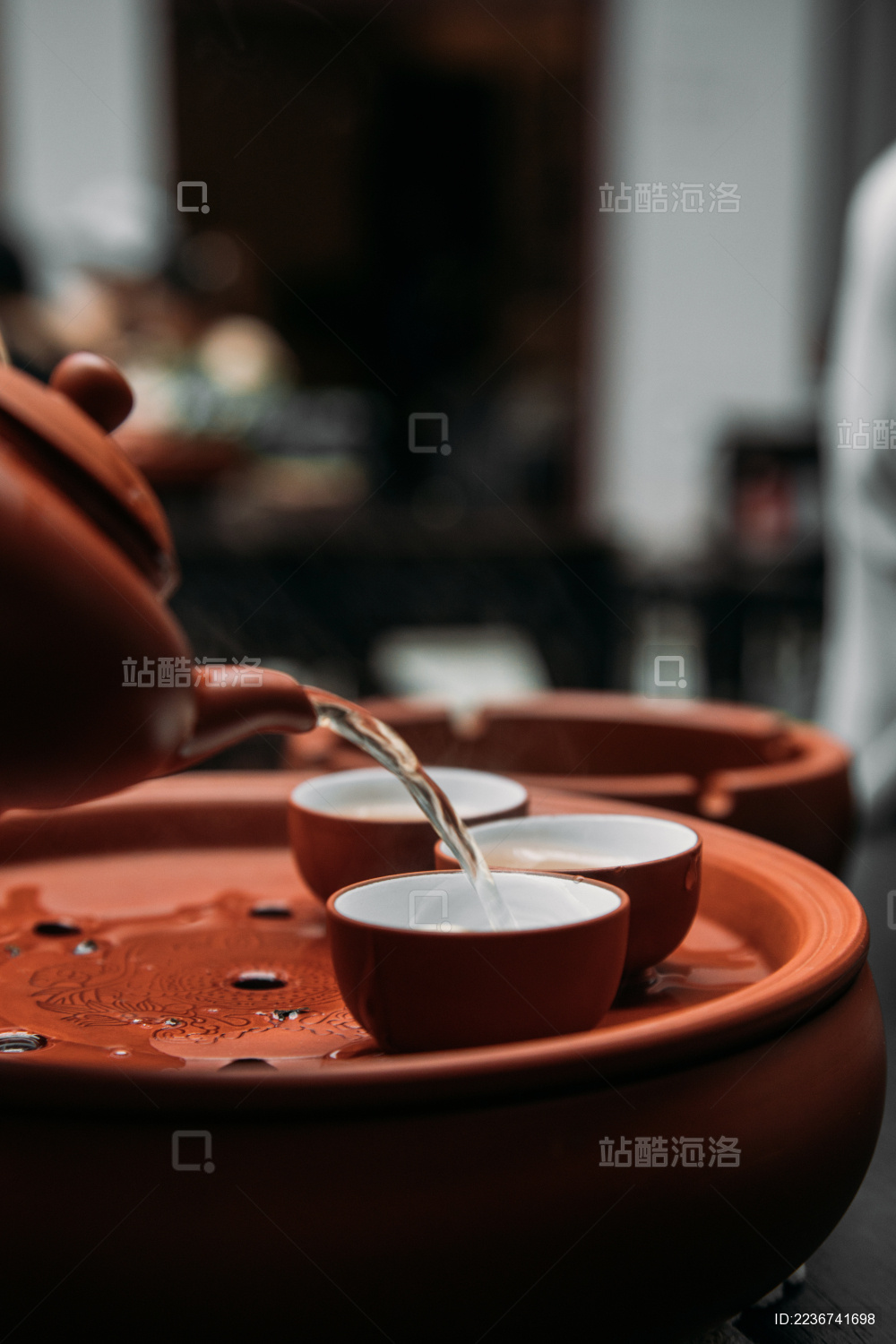 一只手用紫砂茶壶倒把刚泡好的潮州功夫茶倒入茶杯竖图