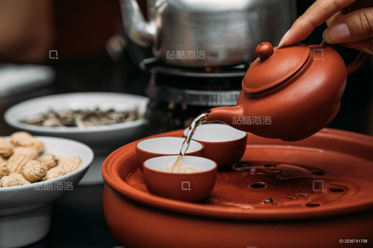 一只手用紫砂茶壶倒把刚泡好的潮州功夫茶倒入茶杯横图