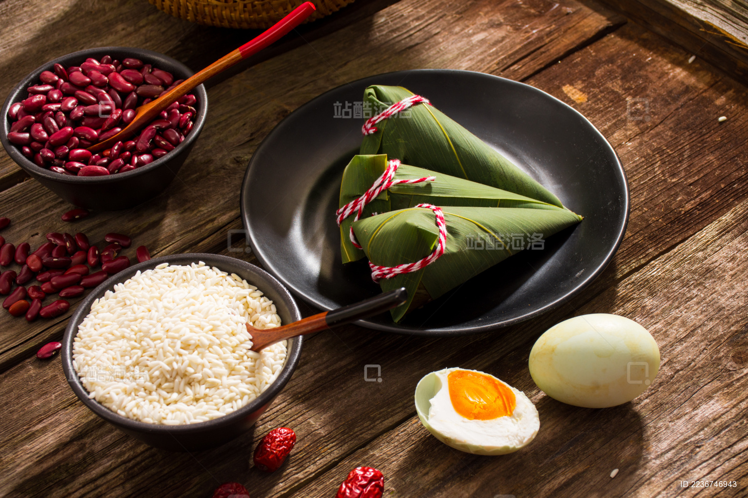 黑色盘子里放着三个新鲜的尖角粽子 旁边放着粽子食材