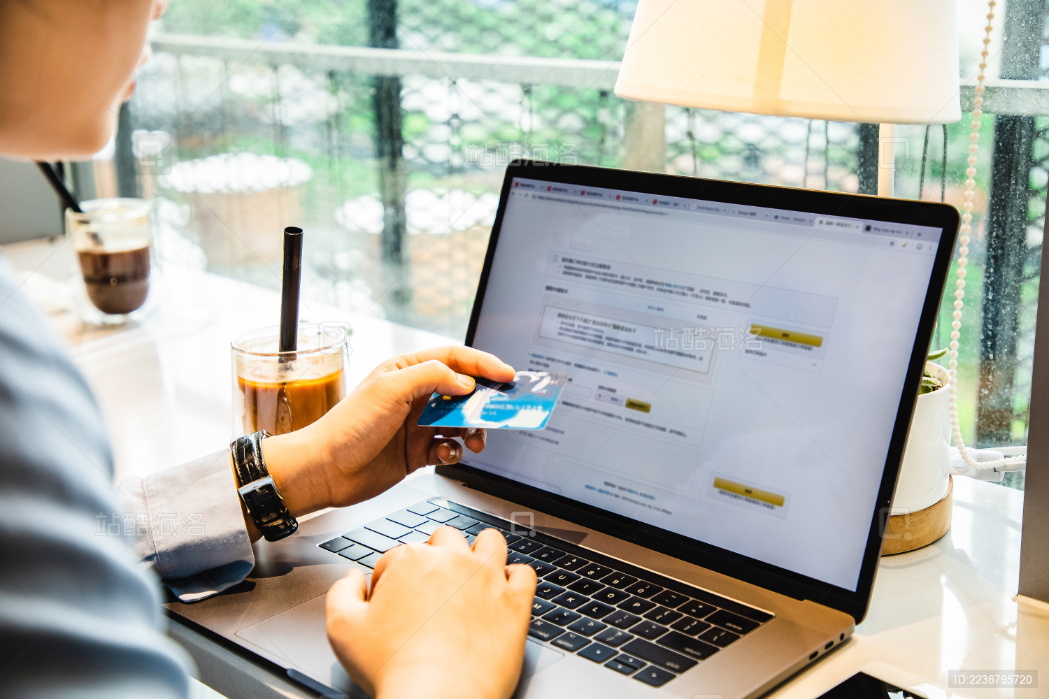 咖啡馆里女性手持信用卡在笔记本电脑键盘上输入信息
