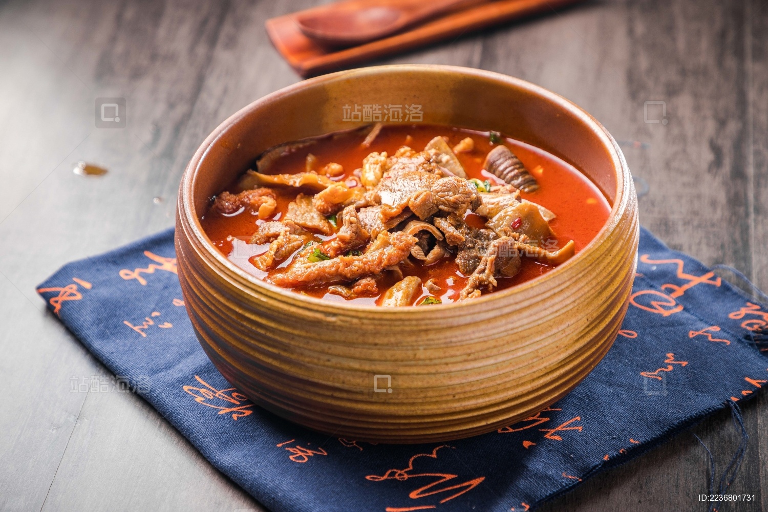 蓝色餐布上有一碗砂锅番茄汁牛杂汤锅