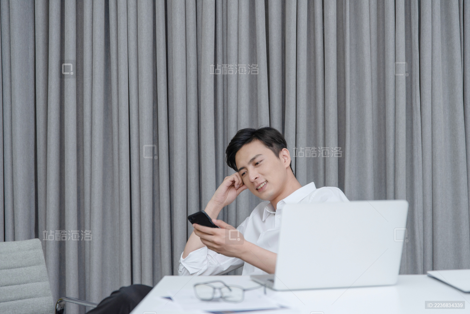 在办公桌前放松地使用手机的年轻男性白领