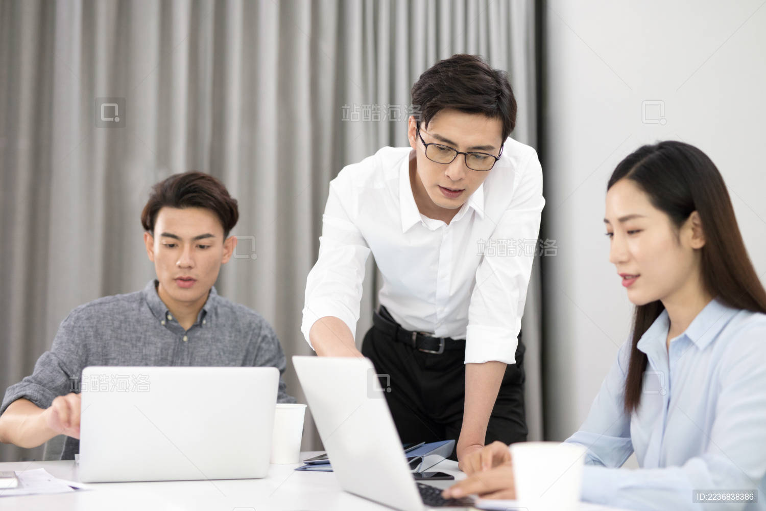 办公室里三位年轻的商务职员正在讨论工作中的相关问题