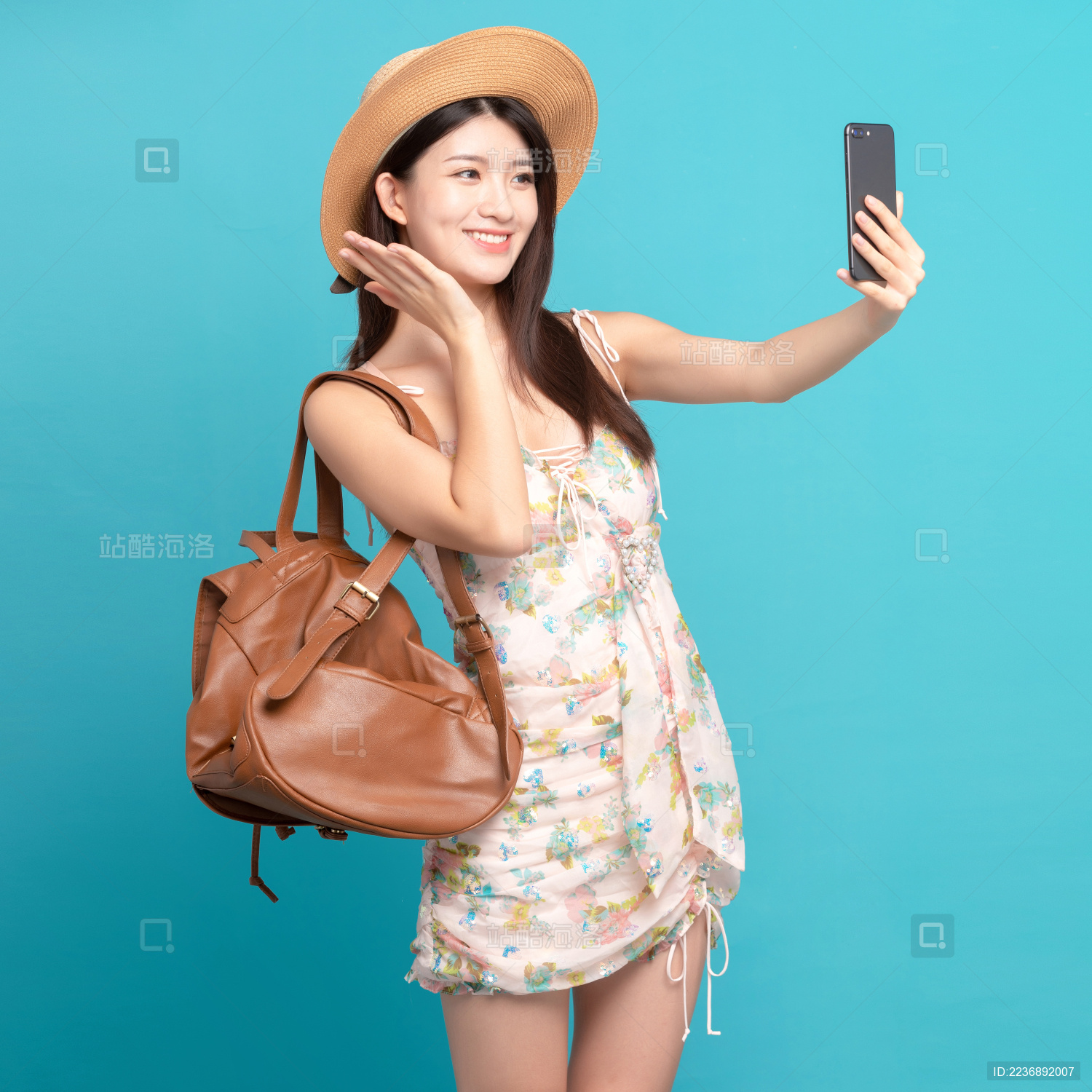  蓝色背景里 正在用手机拍照的美丽东方女孩