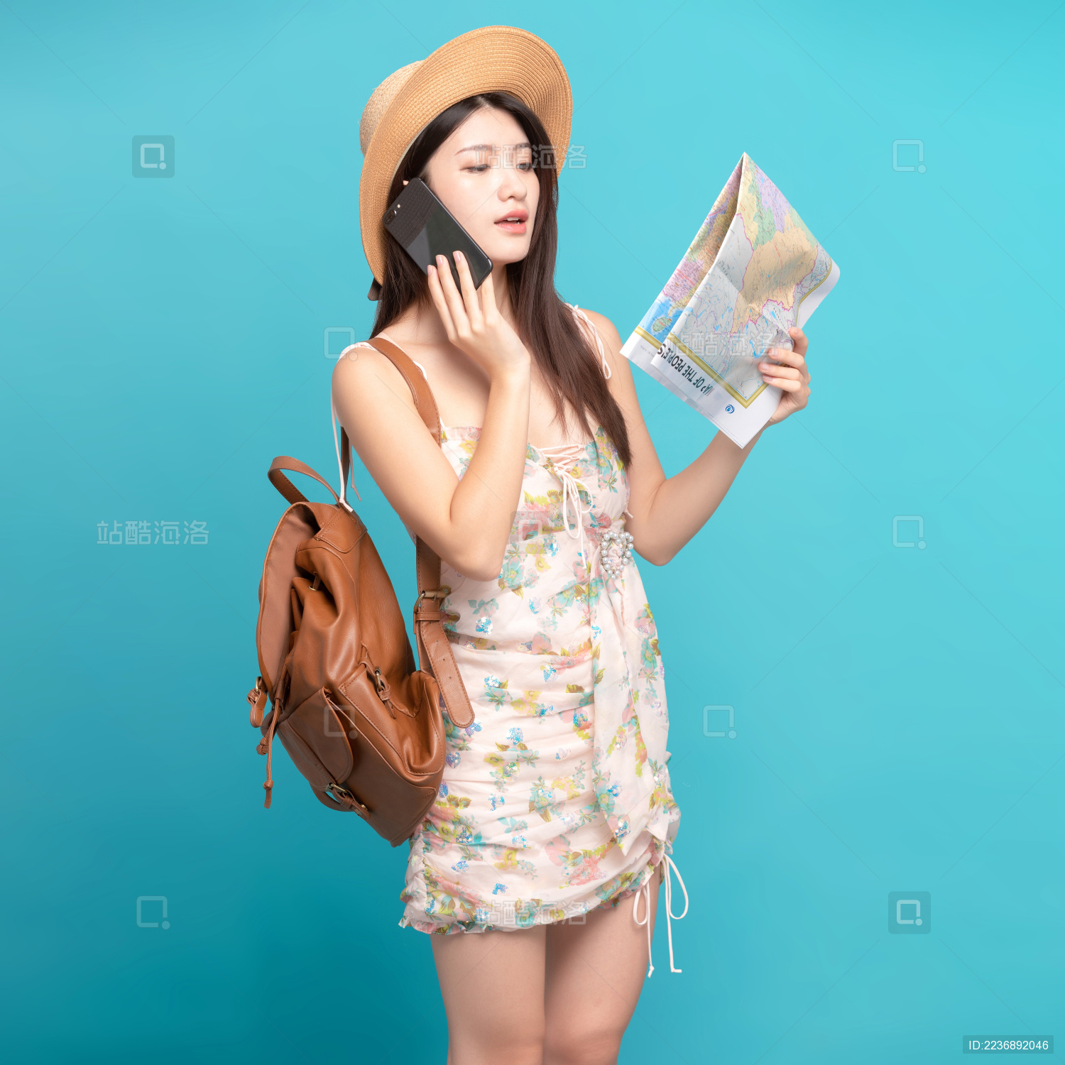 蓝色背景里 边打电话边看地图的美丽东方女孩