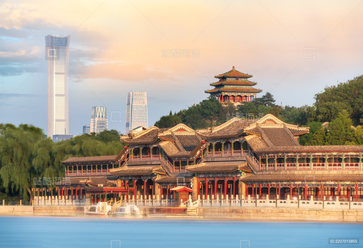 中国北京北海公园蓝色湖面对岸的长廊及远景景山上的万春亭和CBD现代建筑