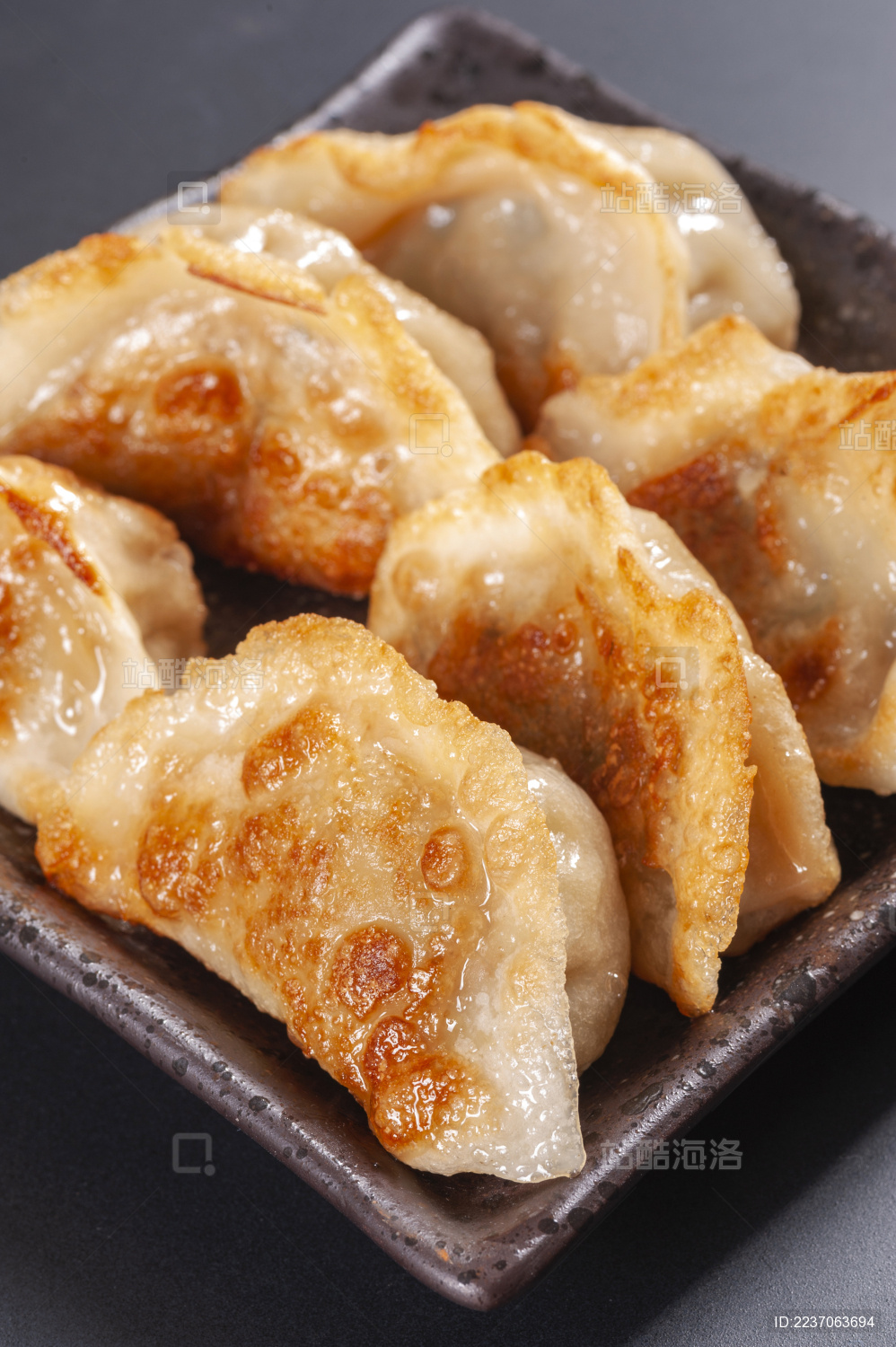 被油煎的金黄色的煎饺盛放在深色碟子中与中国结摆放在桌面上