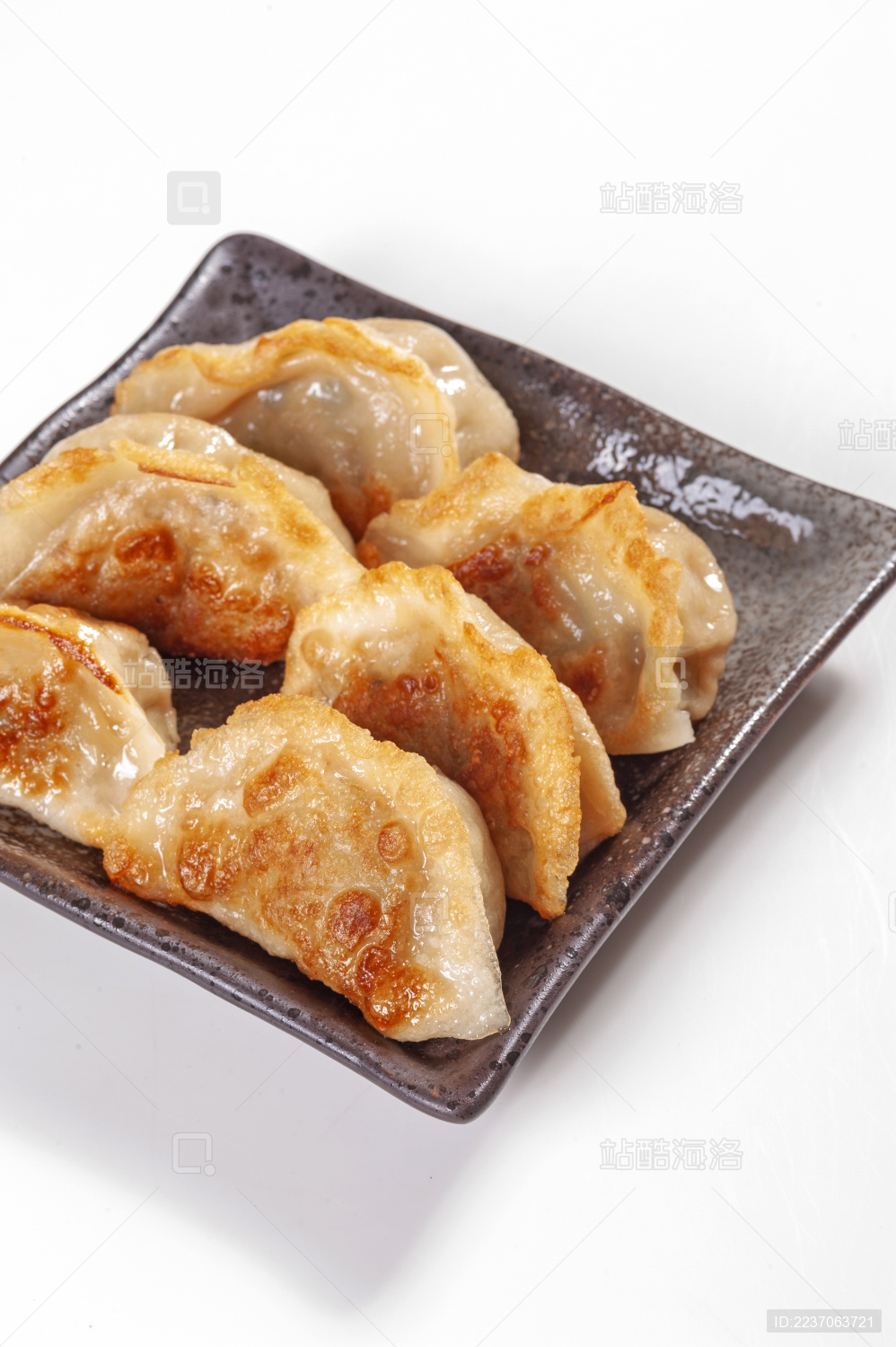 被油煎的金黄色的煎饺盛放在深色碟子中与中国结摆放在桌面上