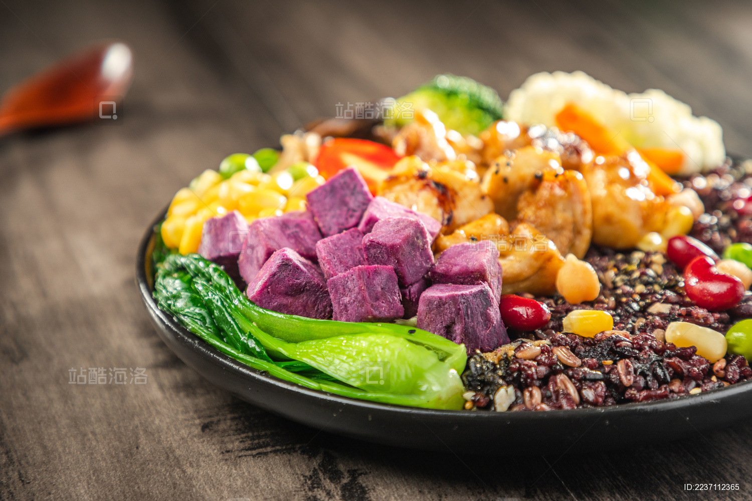  暗色木纹桌上放着一盘煎鸡腿肉黑米饭简餐