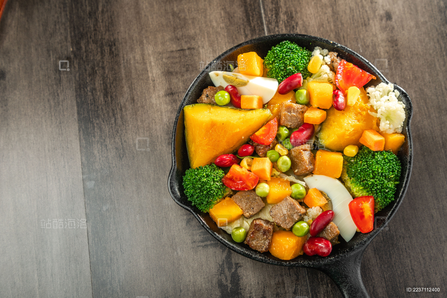 暗色木纹桌面上放着一盘煎牛肉块蔬菜沙拉