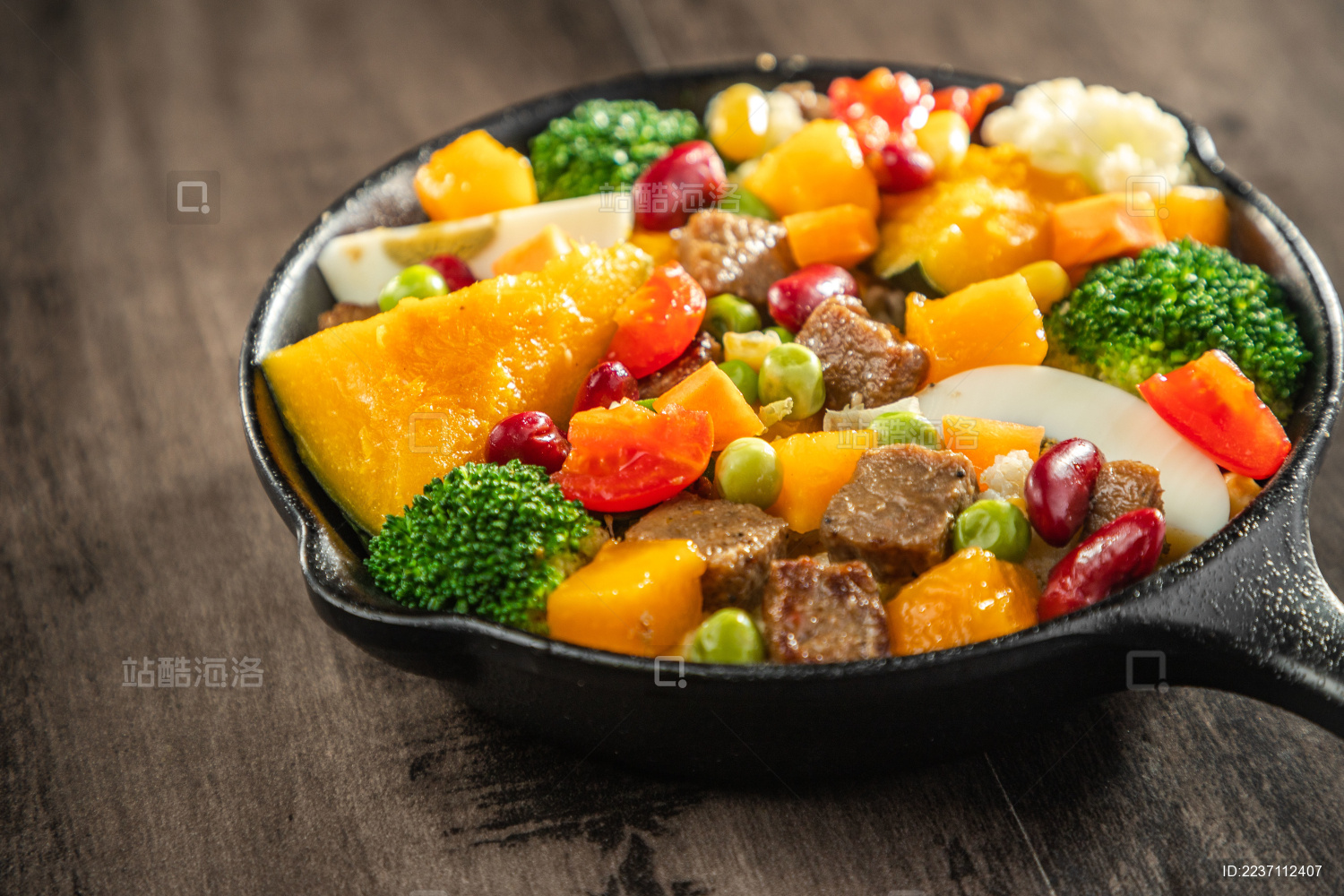 暗色木纹桌面上放着一盘煎牛肉块蔬菜沙拉