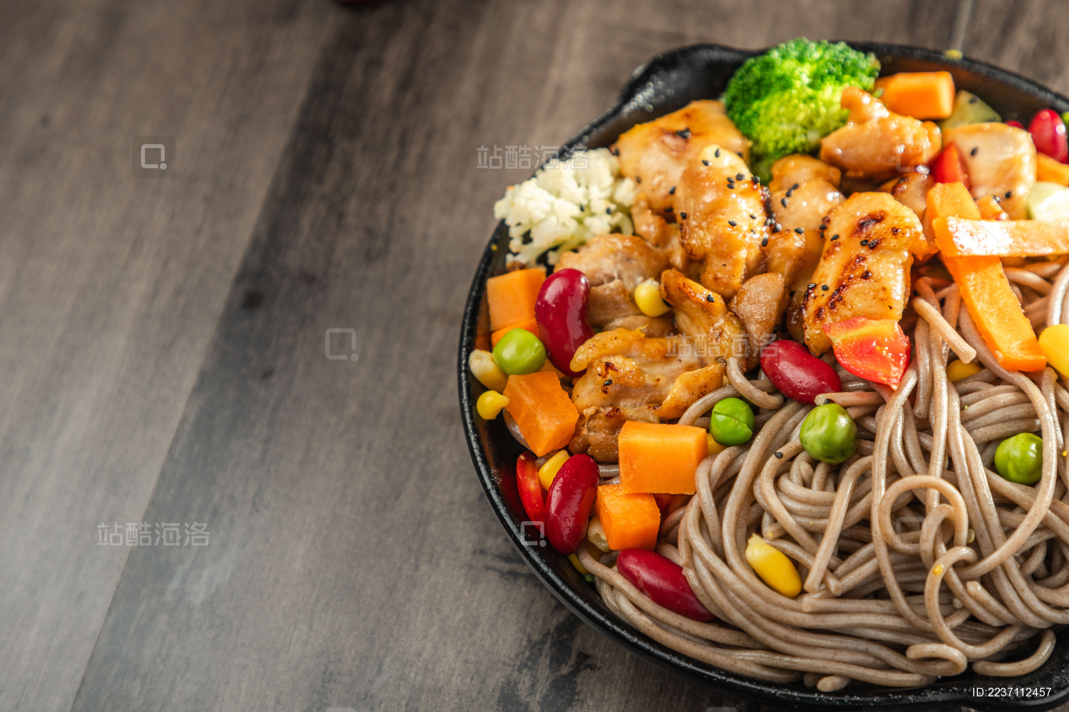 暗色木纹桌面上放着一盘煎鸡腿肉荞麦面